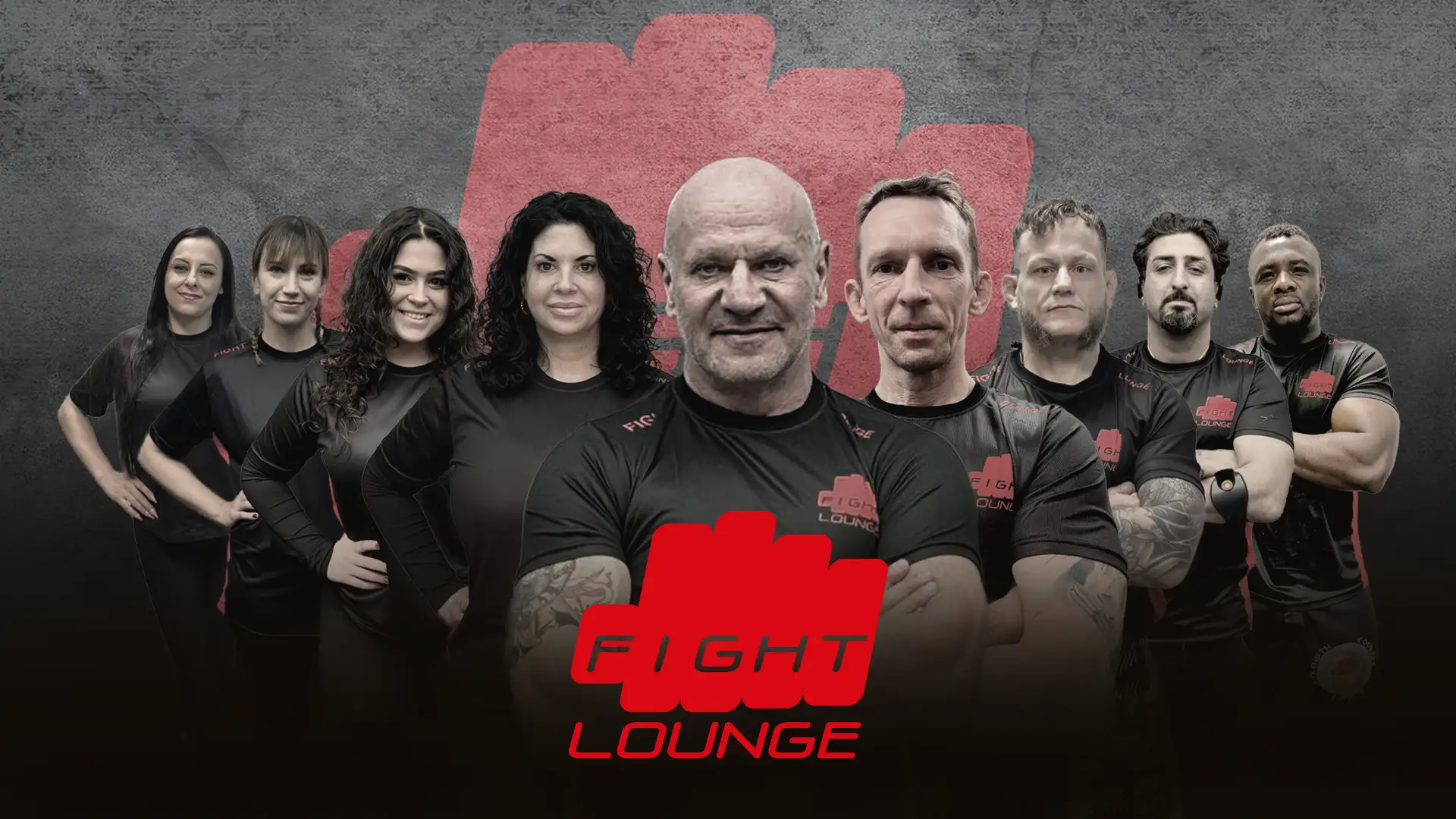 Das Trainer-Team der Fight Lounge: Die Head Coaches und der Kampfsport-Schule für die Standorte Bochum, Dortmund und Hagen posieren vor einem großen roten Faust-Logo auf grauem Hintergrund.